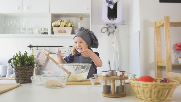 Happy little girl baker going to bake cookies in the kitchen , close up