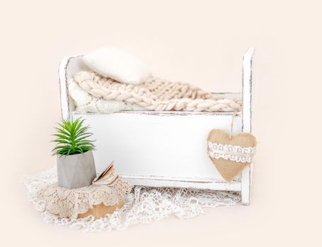 Beautiful white wooden bed furniture for newborn studio photoshoot with fur, pillow decoration. Tiny designed place for infant photo isolated on light pink background