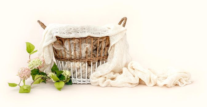 Beautiful basket furniture for newborn studio photoshoot with fur, knitted blanket and flower decoration. Tiny designed place for infant photo isolated on light background