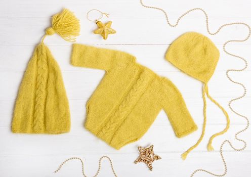 Composition of yellow knitted suit and hats with decorations