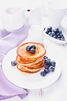 Pancakes with blueberry on a white plate and napkin