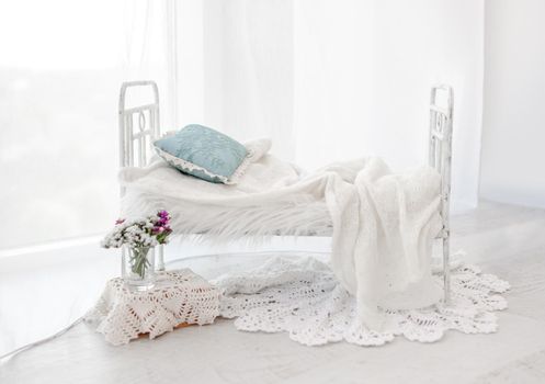 Tiny white bed decor for newborn studio photoshoot with knitted blanket closeup. Infant baby photo furniture