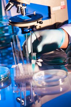 Man is looking into the ocular of microscope, doing reseach