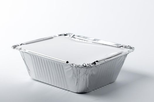 Foil food box with takeaway meal on white background close up