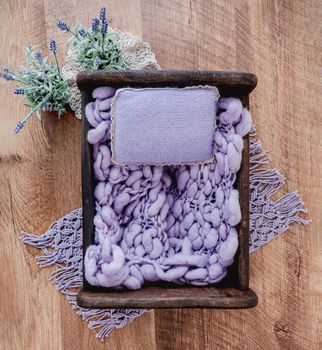 Cute cozy background for newborn photosession. Digital composite with wooden bed filled with knitted purple blanket and pillow