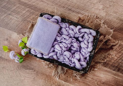 Cute cozy background for newborn photosession. Digital composite with wooden bed filled with knitted purple blanket and pillow