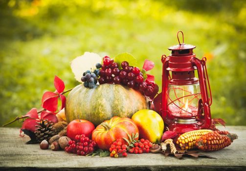 Fruits and nuts, pumpkins on the table outdoor and kerosene lamp - cozy autumn