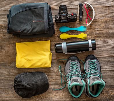Hiking accessories on wooden background, view from top