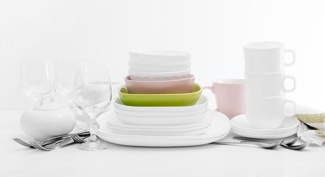 Pile of colourful square dishes and cups with dishcloth