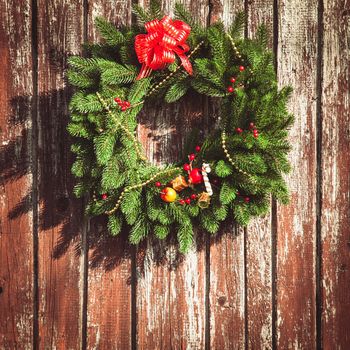 Christmas wreath with decorations on the shabby wooden door.