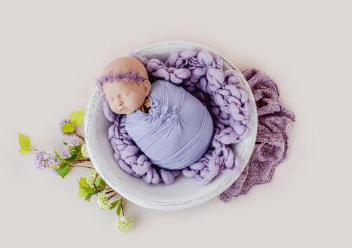 Beautiful backdrop for newborn photosession with flowers hydrangea and swaddled infant manequen for photographer trainings. Digital composite with baby doll model in basin isolated on white background