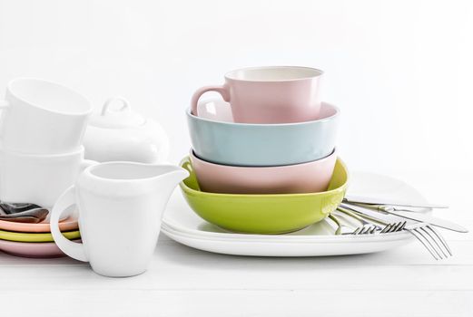 Multicolored ceramic bowls with silver cutlery on white background