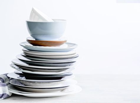 Stack of different porcelain plates on white table