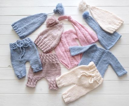 Colorful small knitted clothes for babies composed on the white table