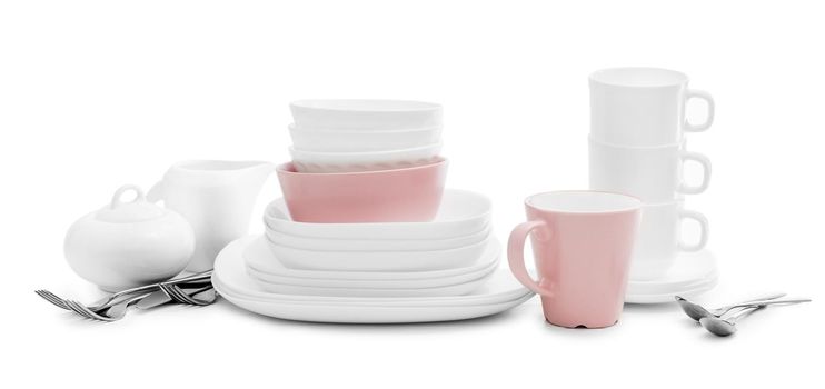 White and pink plates, sugar bowl and mugs isolated on white background. Ceramic tableware.