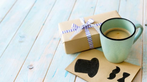 Happy Father's day greeting with cup of tasty coffee and gift box on rustic wooden background. Happy father's day concept. Greetings for father's day