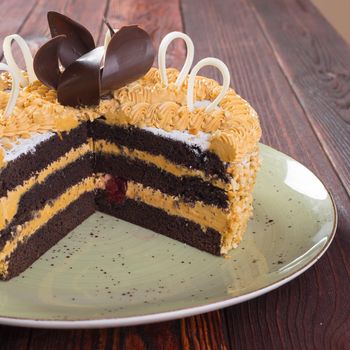 Cut caramel cake on plate on wooden table close up