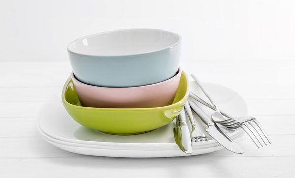 Multicolored ceramic bowls with silver cutlery on white background