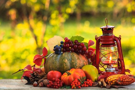 Fruits and nuts, pumpkins on the table outdoor and kerosene lamp - cozy autumn