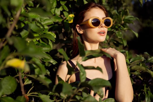 cheerful woman wearing sunglasses green leaves nature summer posing. High quality photo