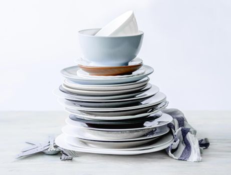 Stack of different porcelain plates on white table