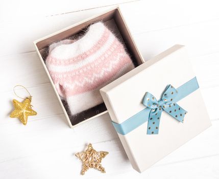 Opened gift box with knitted sweater composed with star decorations