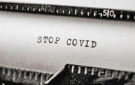 Actual text Stop Covid printed on retro typewriter. Vintage information message using typescript