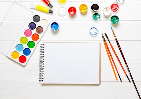 Watercolors and paint brushes with white empty notebook for drawing. Creative copy space. Artist concept