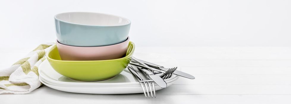 Multicolored ceramic bowls with silver cutlery on white background