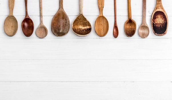 Hand-carved wooden spoons on white wooden background. Wooden kitchenware. Place for text, copyspace. Top view