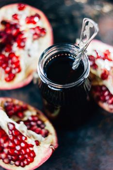 Pomegranate sauce in glass bottle over rustic background