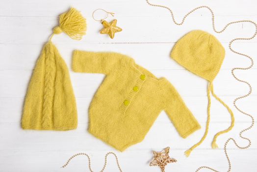 Composition of yellow knitted suit and hats with decorations