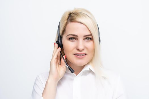 Portrait of cheerful customer support female phone operator in headset, against white brick wall background. Consulting and assistance service call center.
