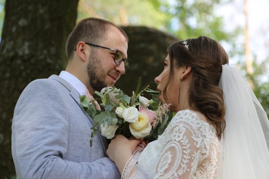 Wedding photo of the bride and groom in a gray-pink color on nature in the forest and rocks