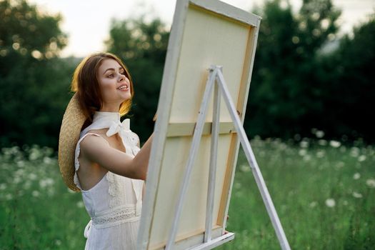 Woman in white dress paints a picture outdoors hobby creative. High quality photo