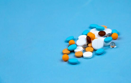 Multi-colored pills on a blue background close-up, with copy space for text.