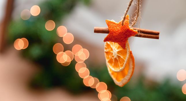Hanging Christmas decoration of dried oranges, tangerine and cinnamon stars with copy space for text. holiday concept. blurred background.