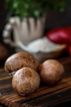 Raw mushrooms on wooden board. Three mushrooms on kitchen