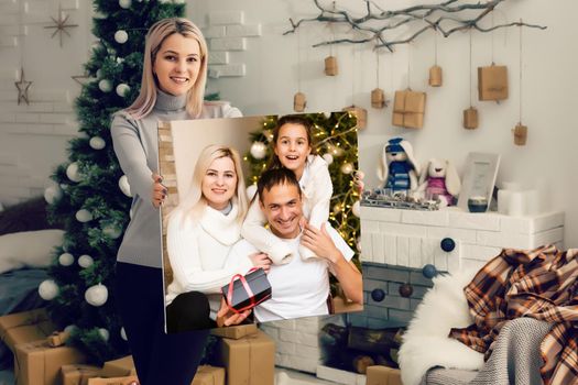woman holding a photo canvas on the background of a Christmas interior.