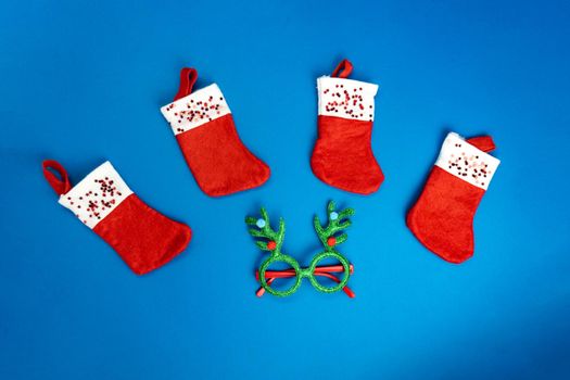 Christmas socks, boots of santa clause, green deer glasses are on blue background, trendy color of the year. New year concept, good for banner, minimalism