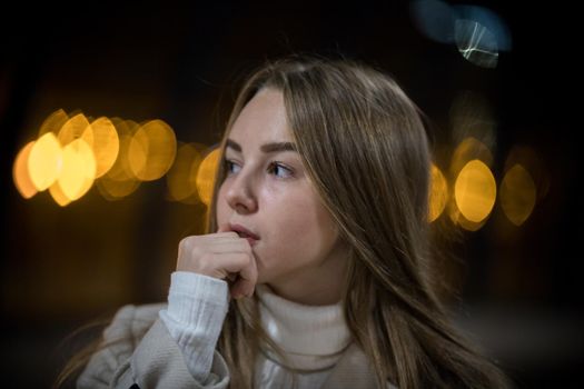 Portrait of young woman in the subway waiting for the train. Looking to the side. Back lights. Close up