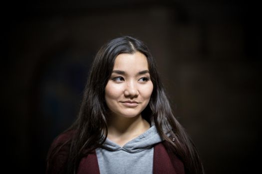 Portrait of young smiling woman on a black background. Looking to the side