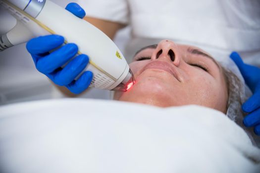 Cosmetology clinic. A client taking procedure. Working with a special tool. Close up