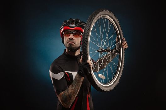 a guy-cyclist in a Bicycle helmet with a Bicycle wheel