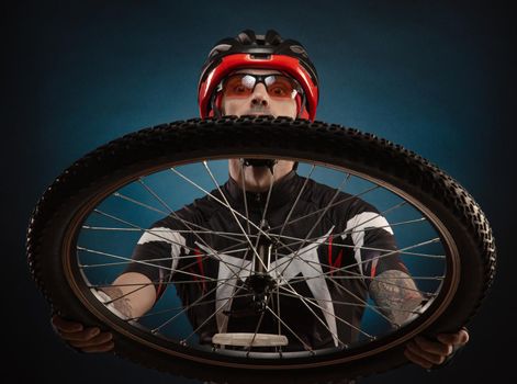 a guy-cyclist in a Bicycle helmet with a Bicycle wheel