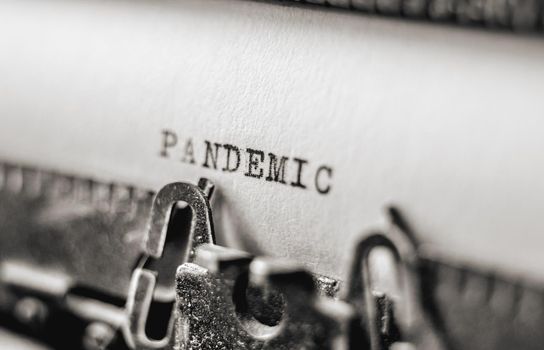 Text Pandemic printed with black inks on old white paper on retro typewriter with typographic font