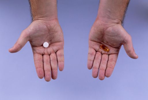 Man hands giving two big pills. White and orange. Make your selection. Health or ill. Choose your side