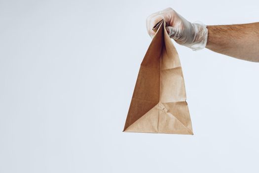 Courier hands in latex gloves giving packed food delivery close up