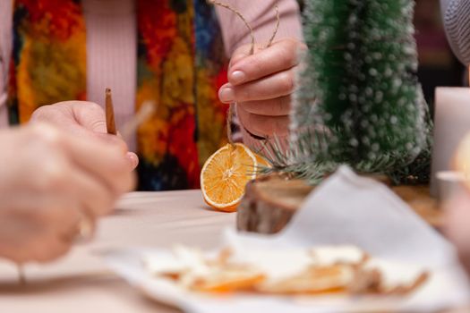 Women's hand making decorations from dried oranges, stars from tangerine and cinnamon. Girls party or meeting.