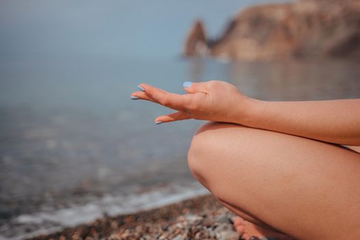 Young woman in swimsuit with long hair practicing stretching outdoors on yoga mat by the sea on a sunny day. Women's yoga fitness pilates routine. Healthy lifestyle, harmony and meditation concept.